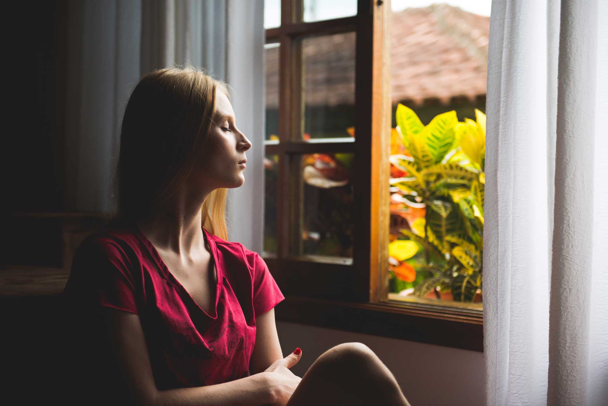 A woman sitting in front of a window looking out.